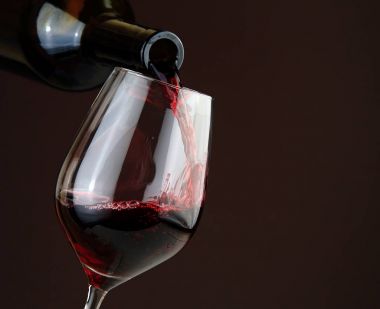 Koyu arka plan üzerinde kırmızı şarap dökme