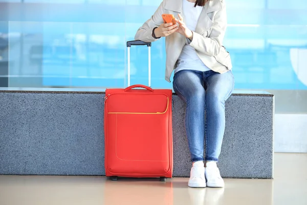 กระเป๋าเดินทางสีแดงใกล้สาวนั่ง — ภาพถ่ายสต็อก