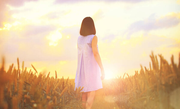 Woman in wheat field at the sunset