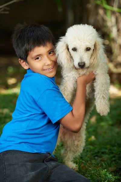 Маленький улыбающийся мальчик с собакой-пуделем — стоковое фото