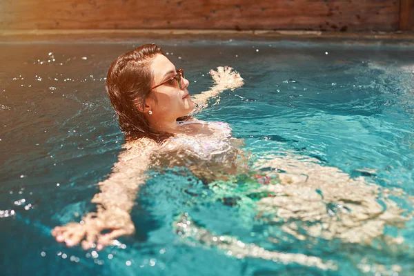 Mujer joven nadando en la piscina de agua azul — Foto de Stock