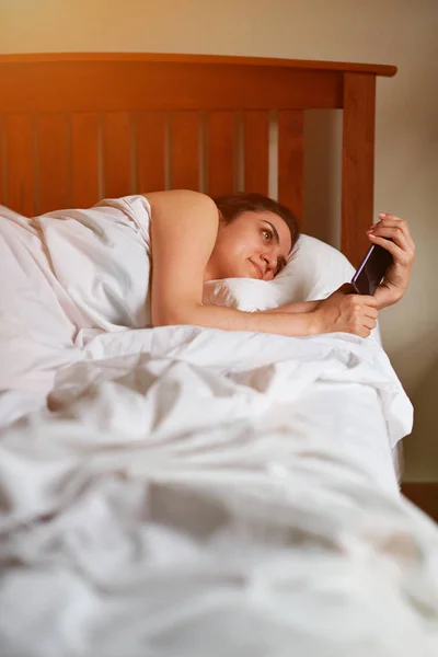 Spansktalande kvinna med smartphone i sovrum — Stockfoto