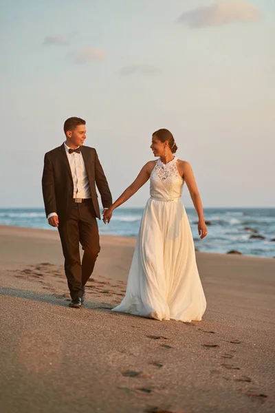 Šťastný ženich a nevěsta chodit na pláži — Stock fotografie