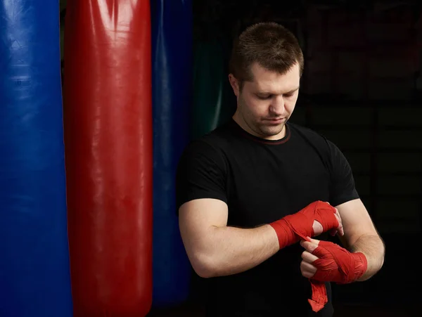 Boxing man applying hand bandage