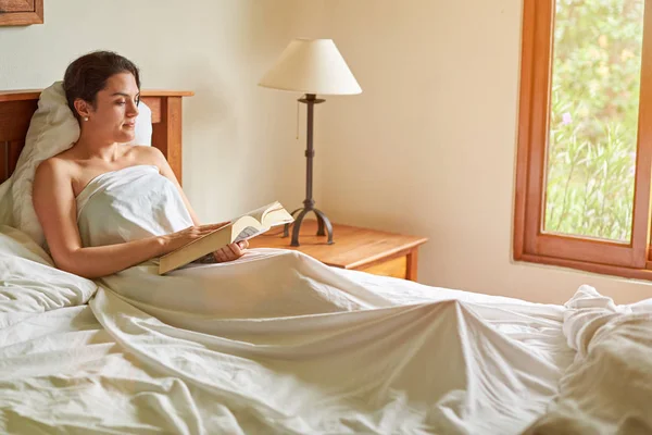 Woman with book in bed room