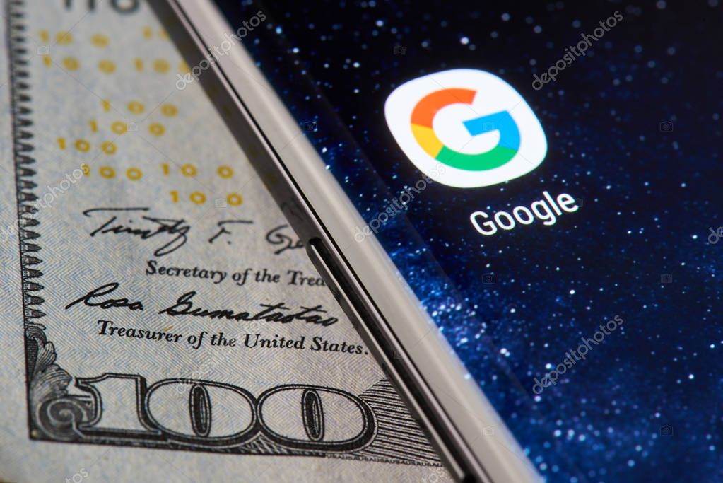 New york, USA - April 11, 2018: Google icon app on smartphone close-up on dollar currency background