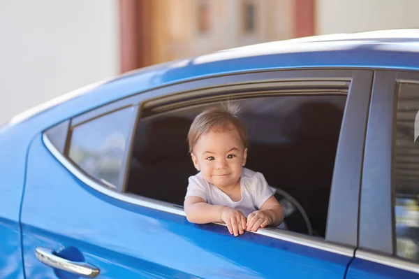 Onnellinen vauva tyttö katselee auton ikkunasta — kuvapankkivalokuva