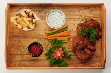 Ahşap tepside kızarmış tavuk bacağı.