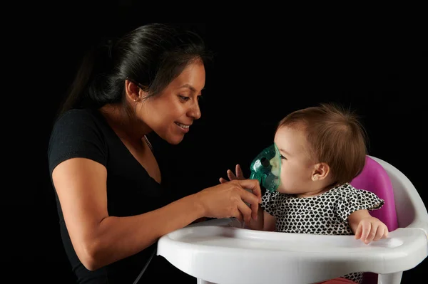 Jonge vrouw houdt inhalator op kind gezicht — Stockfoto