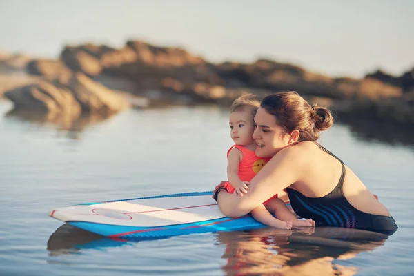 Joven mamá con bebé en tabla de surf —  Fotos de Stock