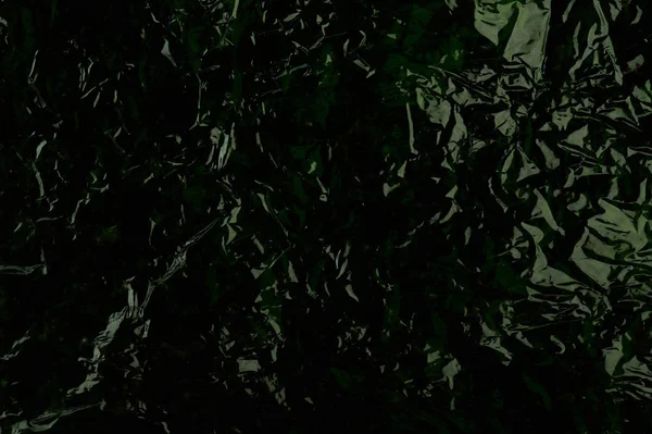 Dark green shiny plastic background close up view