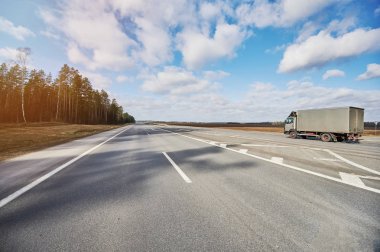 Güneşli bir günde otoyolda giden bir kamyonet var.