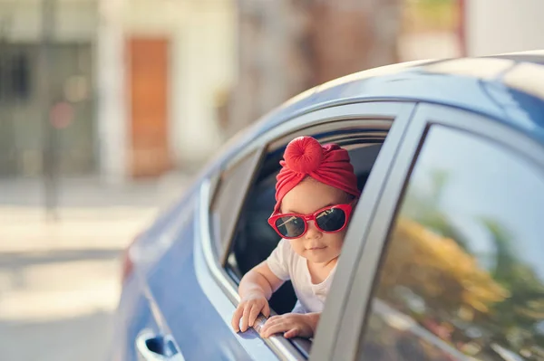 赤ちゃん女の子でサングラス旅行車と窓から見て — ストック写真