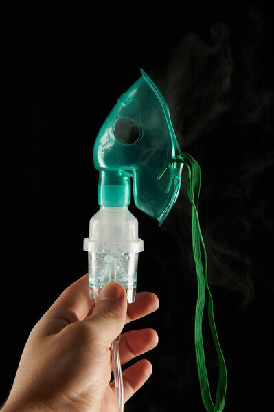 Рука держит пластиковую маску вблизи вид на черном фоне
