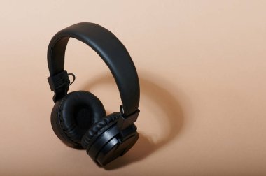 Üst görünümde bej arkaplanda siyah kulaklıklar