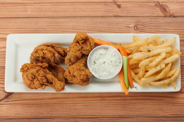 Kızarmış tavuk ve beyaz sos ve ahşap masa manzarasında kızarmış patates kızartması.