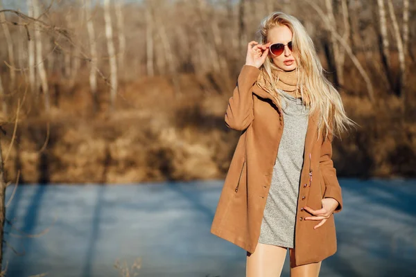 Menina bonita em um casaco posando contra o fundo de uma natureza de primavera — Fotografia de Stock