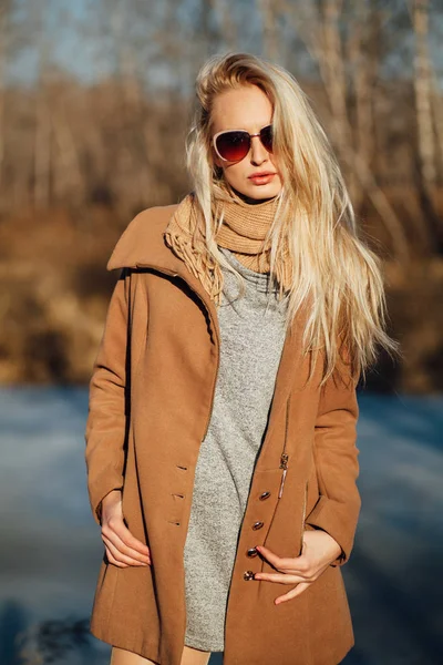Belle fille dans un manteau posant sur le fond d'une nature printanière Photo De Stock