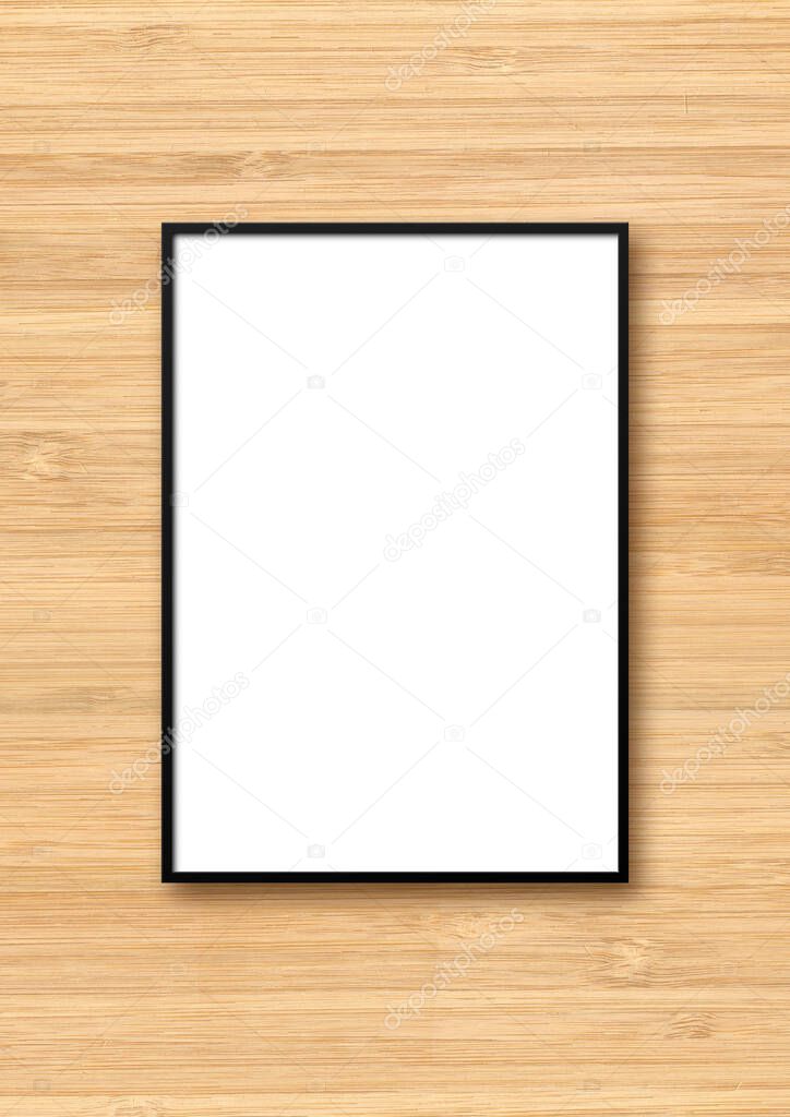 Black picture frame hanging on a light wooden wall. Blank mockup template