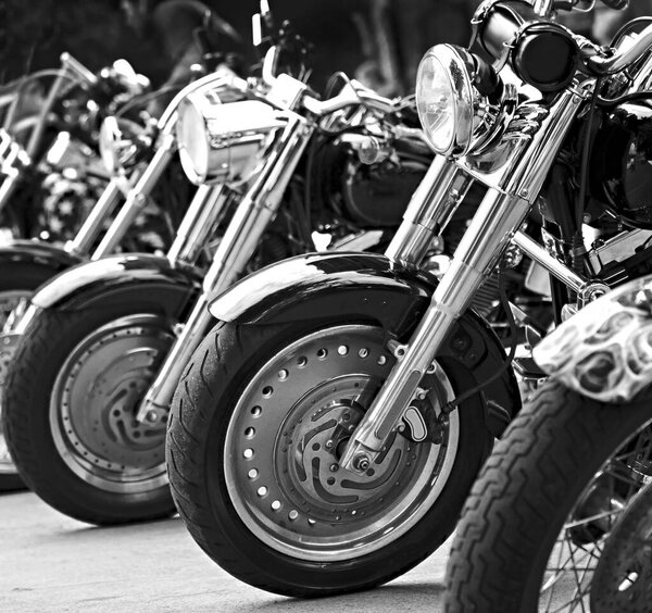 Group motorbikes parked together on outdoors. Black and white photography.