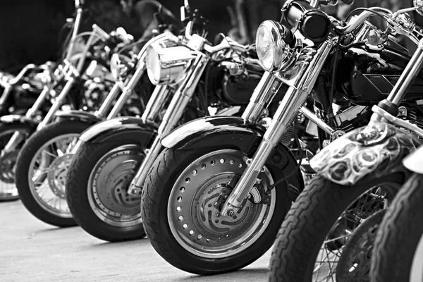 Group motorbikes parked together on outdoors. Black and white photography.