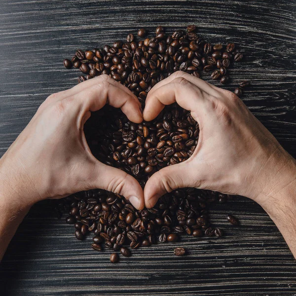 Hands holding coffee beans in shape of heart — Stock Photo, Image