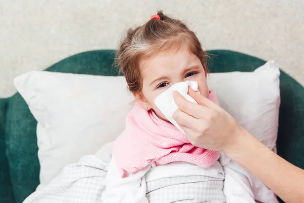 Little girl with flu blowing nose