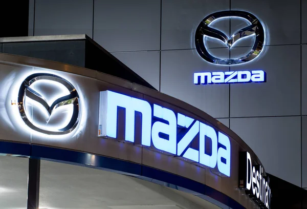 Vancouver. Canada - January 9, 2018: Mazda logo on the facade of official dealer office. Mazda Motor Corporation is a Japanese car brand, automotive manufacturer. Night shot with logos illuminated. — Stock Photo, Image