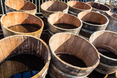 Stacked old wooden half barrels at gerden store is about to have second life as a flower planters or garden decoration. clipart