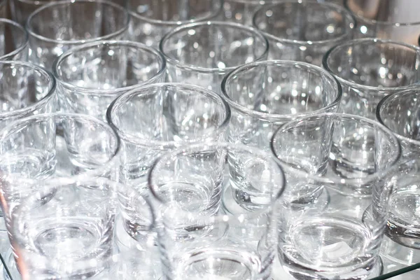 Array of shot glasses on white table - metallic colors. Glasses side by side and reflecting into each other.