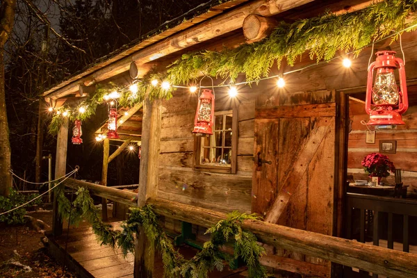 Mały i przytulny domek kabina na zewnątrz z lampkami świątecznymi. Idealny obraz, który przywołuje ducha wakacji. — Zdjęcie stockowe