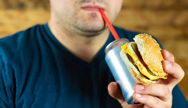 Homem com hambúrguer e lata de bebida pop . — Fotografia de Stock