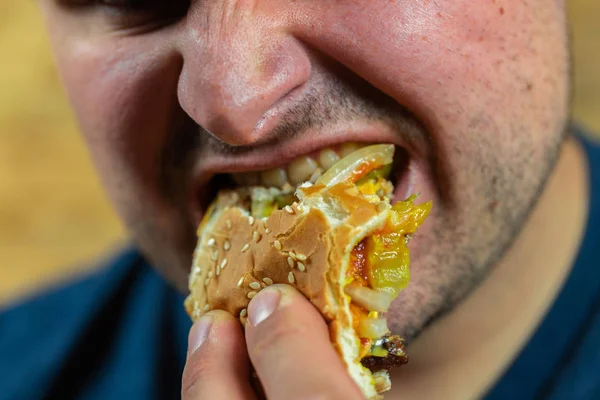Adam lezzetli hamburgerinin tadını çıkarıyor.. — Stok fotoğraf