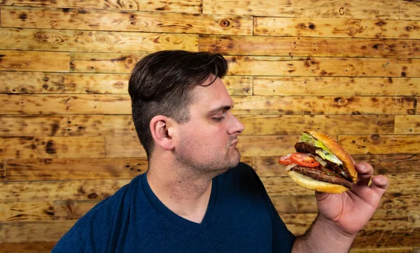 Joven hombre guapo está posando con su sabrosa hamburguesa y a punto de disfrutarlo . —  Fotos de Stock