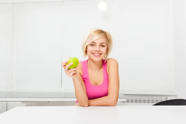 Женщина зеленое свежее яблоко на кухне у себя дома — стоковое фото