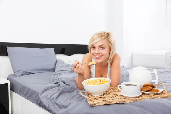Breakfast in bed, young woman lying on bed — Stock Photo, Image