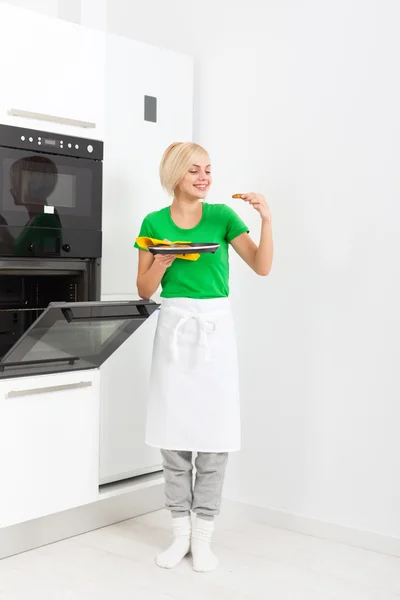 Mujer cocina sabor galletas, hornear tomando de la bandeja del horno —  Fotos de Stock