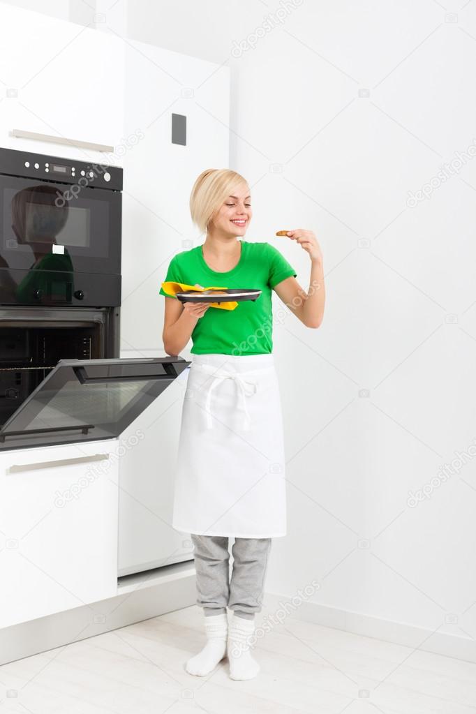 woman cooking taste cookies, baking taking from oven tray
