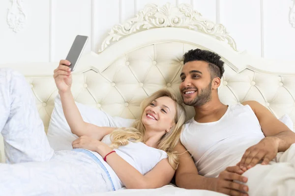 Ungt par ligga säng ta Selfie foto — Stockfoto