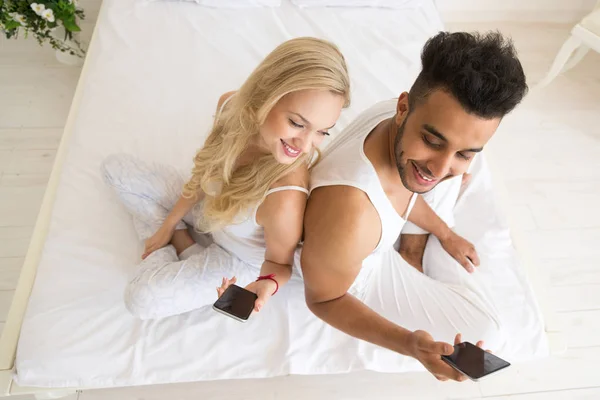 Unga paret sitter i sängen — Stockfoto