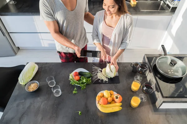 Mladý pár v kuchyni, asijské ženy vaření jídlo snídaně, hispánský člověku Ukázat chytrý mobil — Stock fotografie