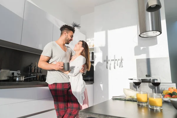 Casal jovem abraço na cozinha, homem hispânico e mulher asiática abraço manhã pequeno-almoço — Fotografia de Stock