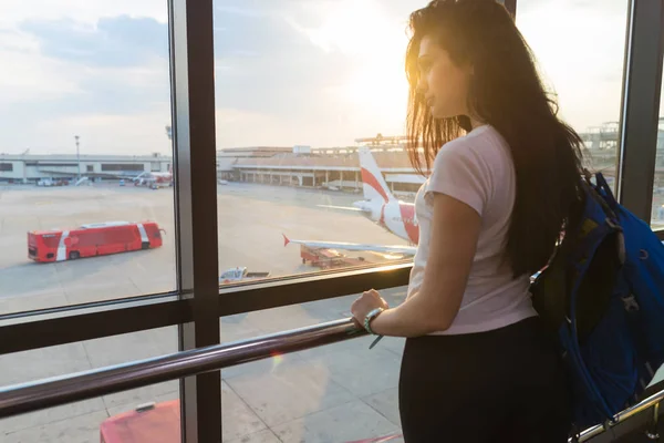 Ung flicka i flygplatsens vänthall titta i fönster plan väntar på avgång lyckligt leende kvinna — Stockfoto