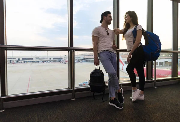 Молодая пара в аэропорт зал ожидания вылета счастливые улыбки, мужчина и женщина полет — стоковое фото #142254160
