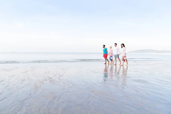 ビーチの夏休み、海辺を歩いて幸せな笑みを浮かべている友人に若い人々 のグループ — ストック写真