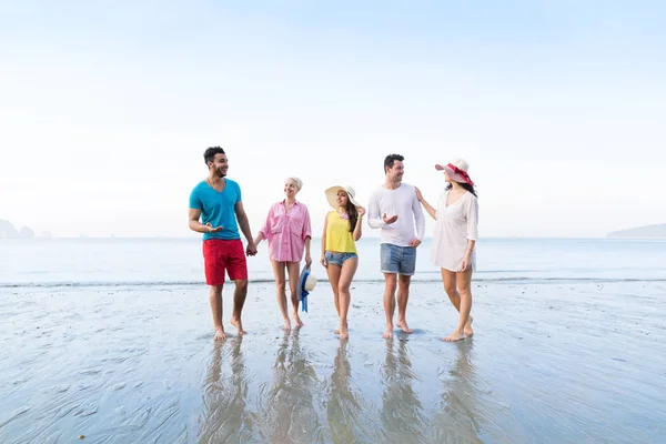 ビーチの夏休み、海辺を歩いて幸せな笑みを浮かべている友人に若い人々 のグループ — ストック写真