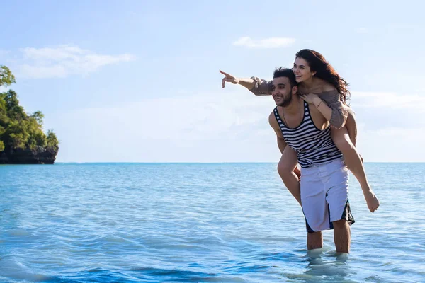 Para plaża wakacje, mężczyzna nosić kobieta punkt palcem, aby skopiować miejsca, piękny młody zadowolony mężczyzna i kobieta Smile — Zdjęcie stockowe
