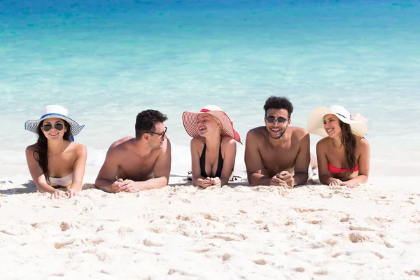 Группа молодых людей на пляже летние каникулы, счастливые улыбающиеся друзья, лежащие песчаный берег — стоковое фото