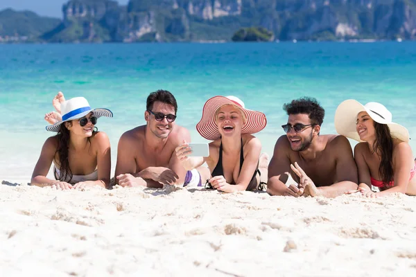 Gruppo di giovani in vacanza estiva sulla spiaggia, felici amici sorridenti sdraiati sul mare di sabbia — Foto Stock