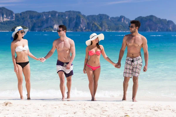 Junge Leute im Sommerurlaub am Strand, zwei glückliche lächelnde Freunde, die am Meer spazieren gehen — Stockfoto